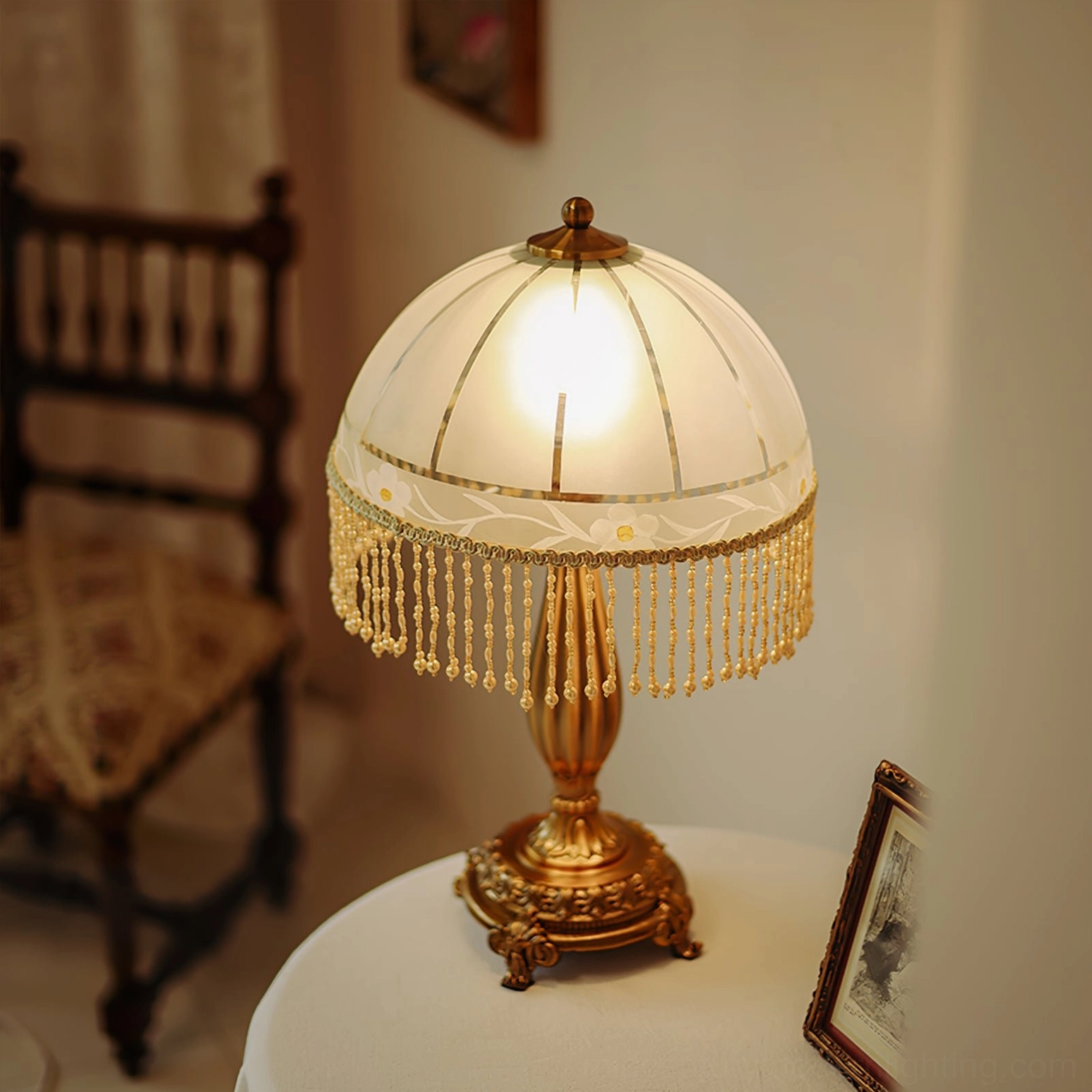 Tassel flower lamp accent piece on round fabric side table with framed photo and soft interior lighting