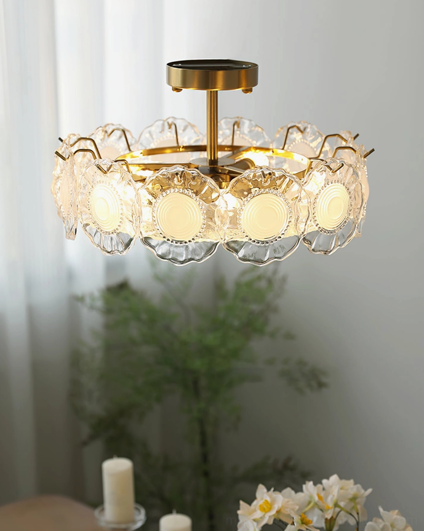 Unlit brass and textured glass ceiling lamp in indoor space with green plants and decorative candles