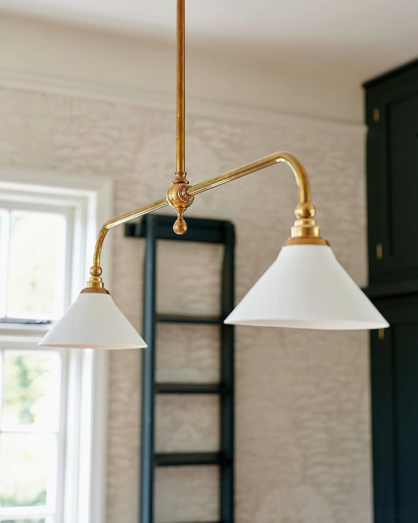 Theron dual-arm dining chandelier with conical shades positioned over cozy dining nook with dark green cabinetry, low-angle interior view