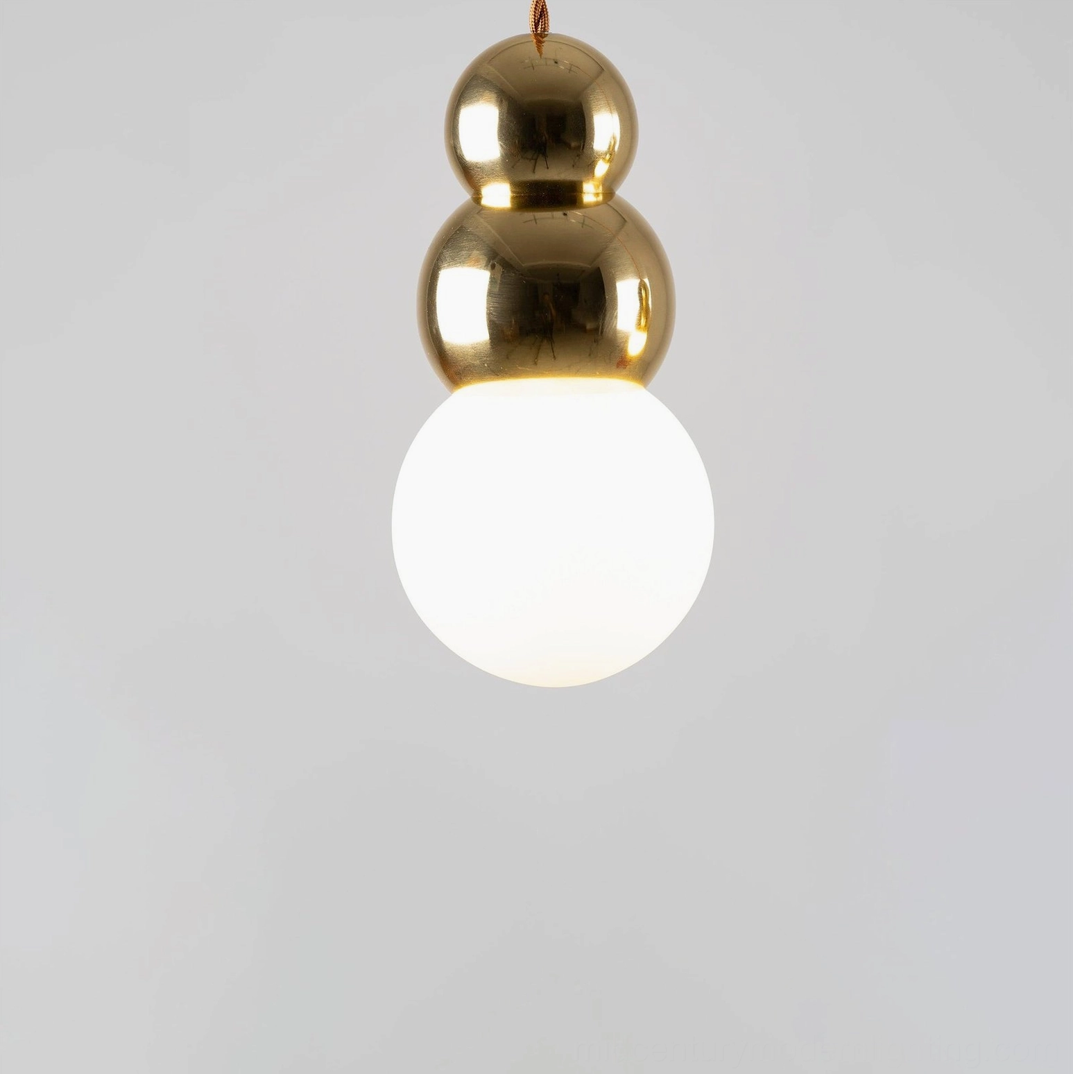 Triple ball pendant light fixture, three polished gold spheres with large frosted white bulb, close-up view