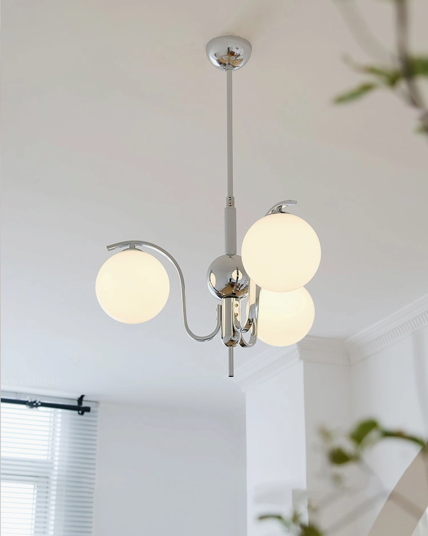 3-head glass globe chandelier with warm glowing shades and compact chrome frame in bright apartment