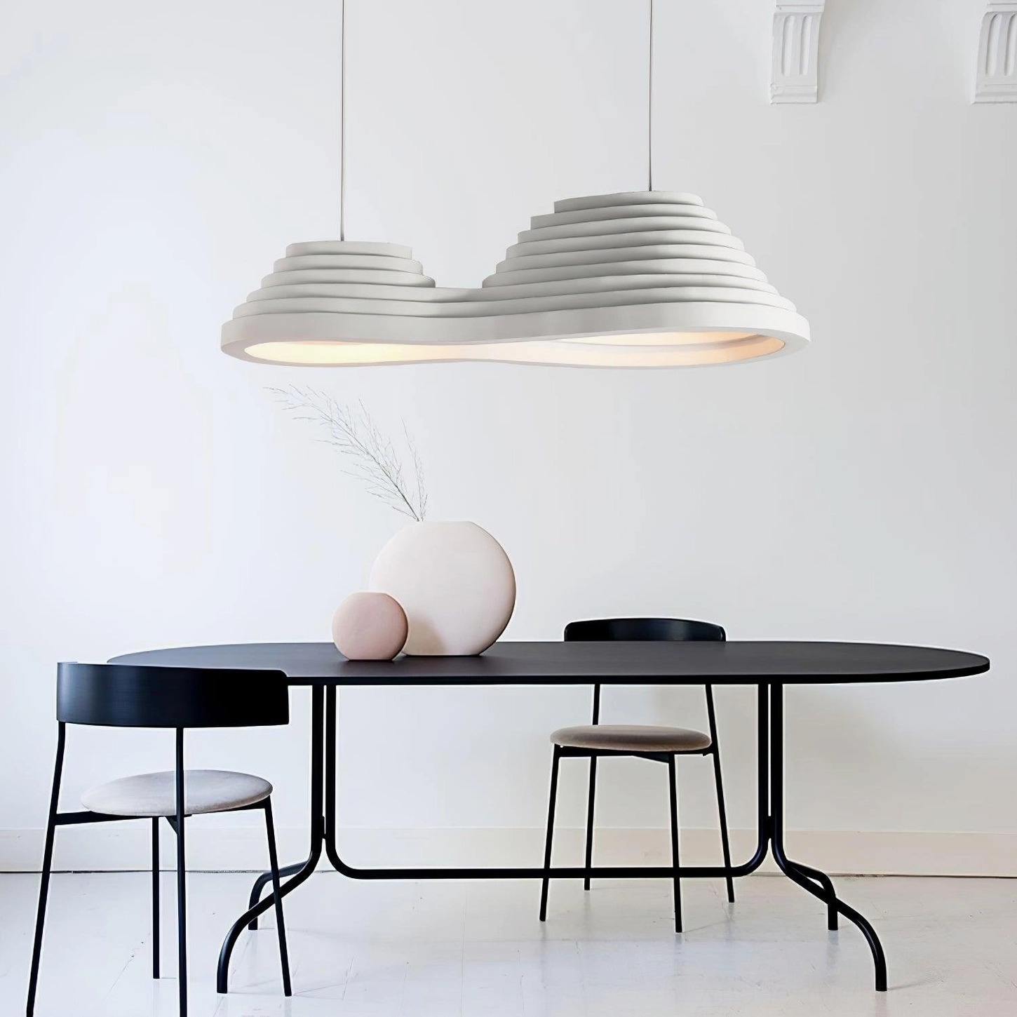 Organic layered pendant lamp suspended over minimalist dining table in modern home with warm neutral decor