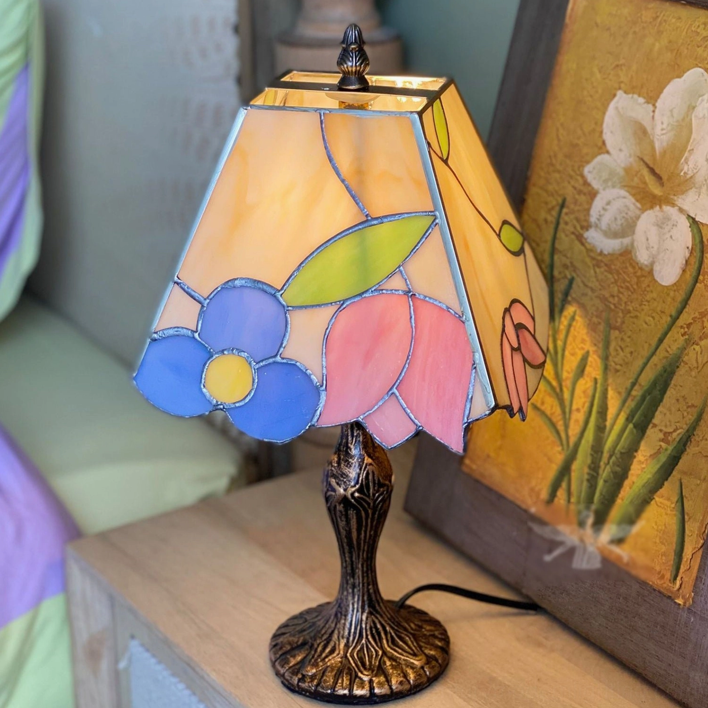 Tiffany floral glass lamp on side table beside large botanical artwork in vintage interior