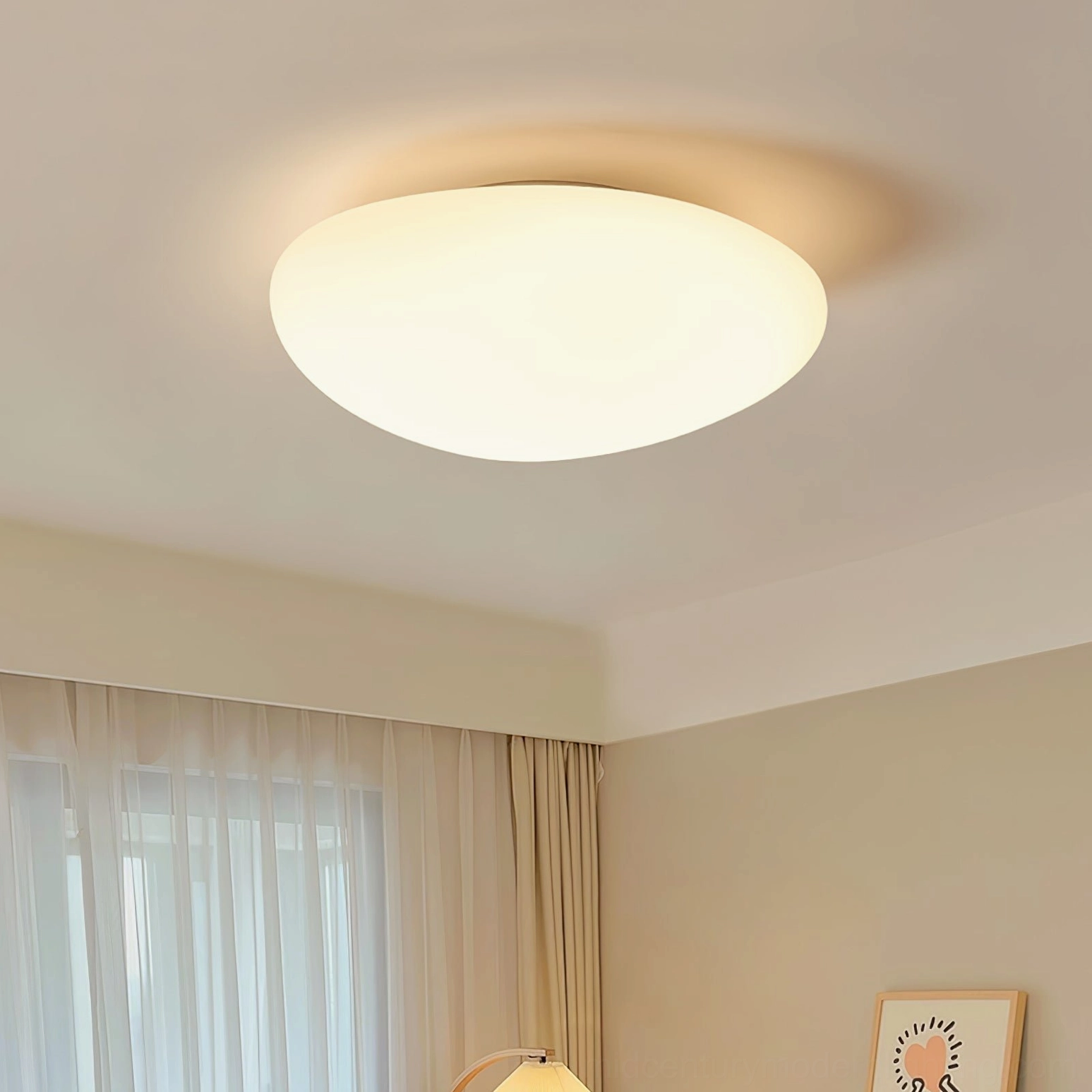 Lit Toan LED ceiling lamp in contemporary bedroom with artwork, warm glowing matte white dome fixture