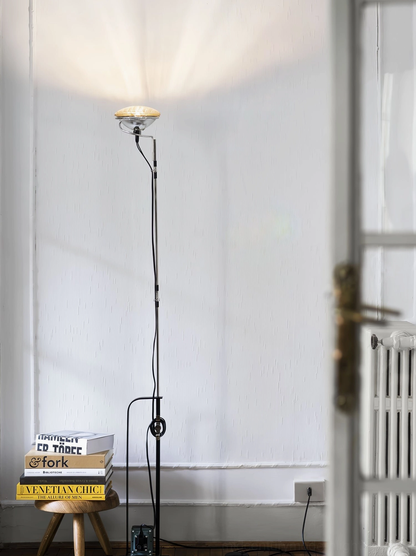 Toio black floor lamp in modern residential entryway with radiator and warm uplighting