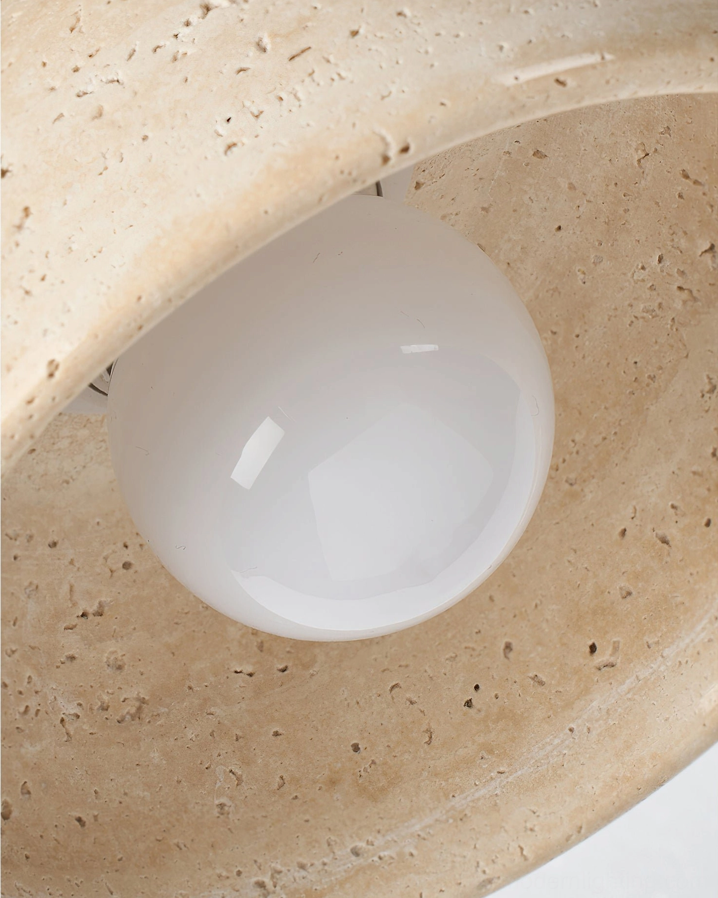 Bottom view of travertine pendant lamp showing interior structure and exposed globe light bulb