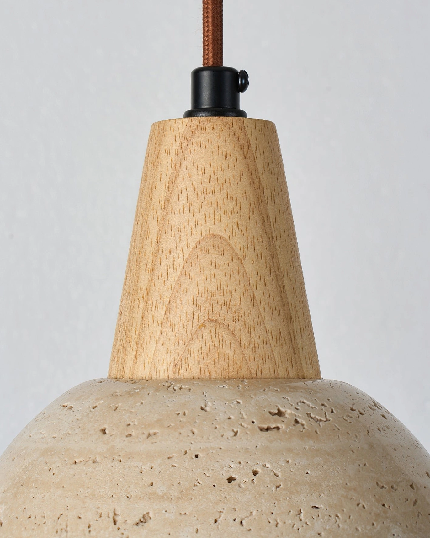 Travertine and wood pendant light mounted in minimalist interior setting with neutral decor elements