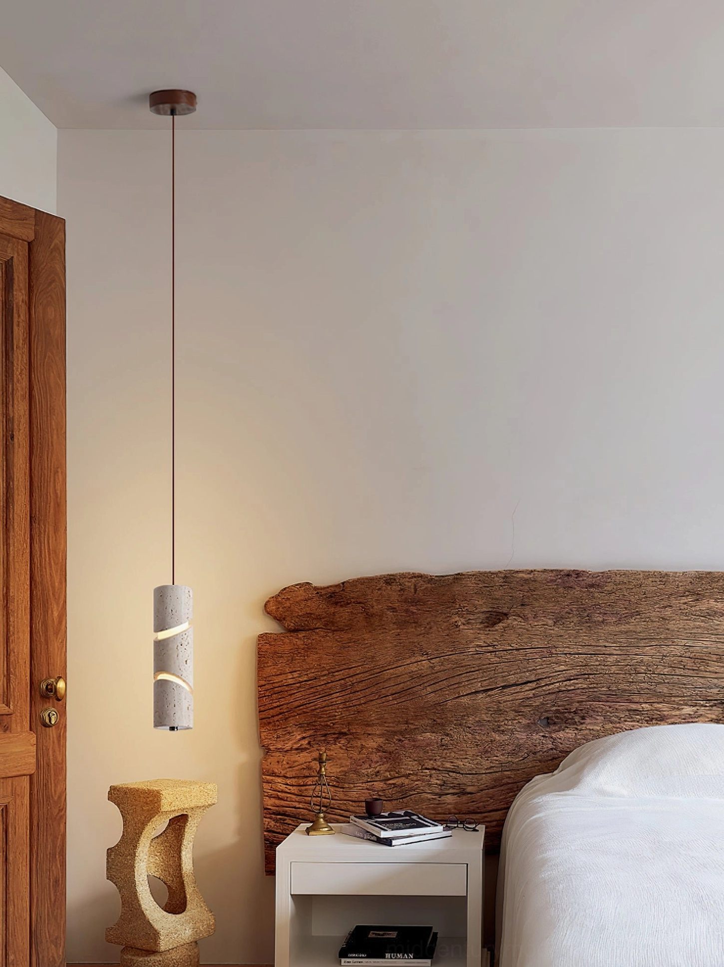 Wide interior shot of travertine sculptural pendant lamp illuminating modern master bedroom with wooden headboard