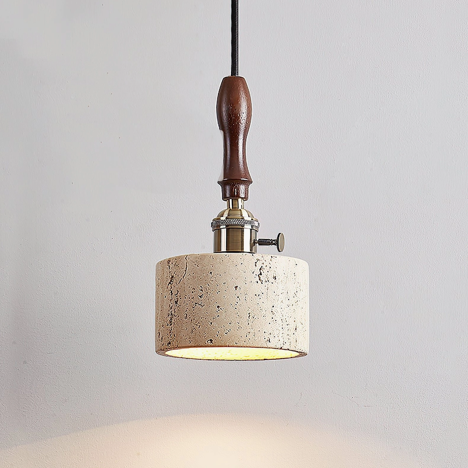 Close-up side view of travertine pendant light highlighting brass switch knob and wooden handle detail