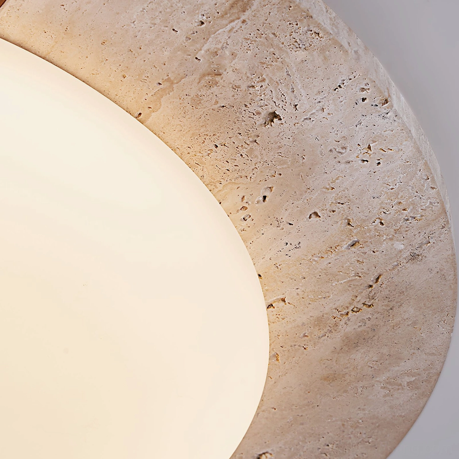 Macro close-up detail shot showing porous yellow travertine stone texture and matte acrylic light diffuser surface