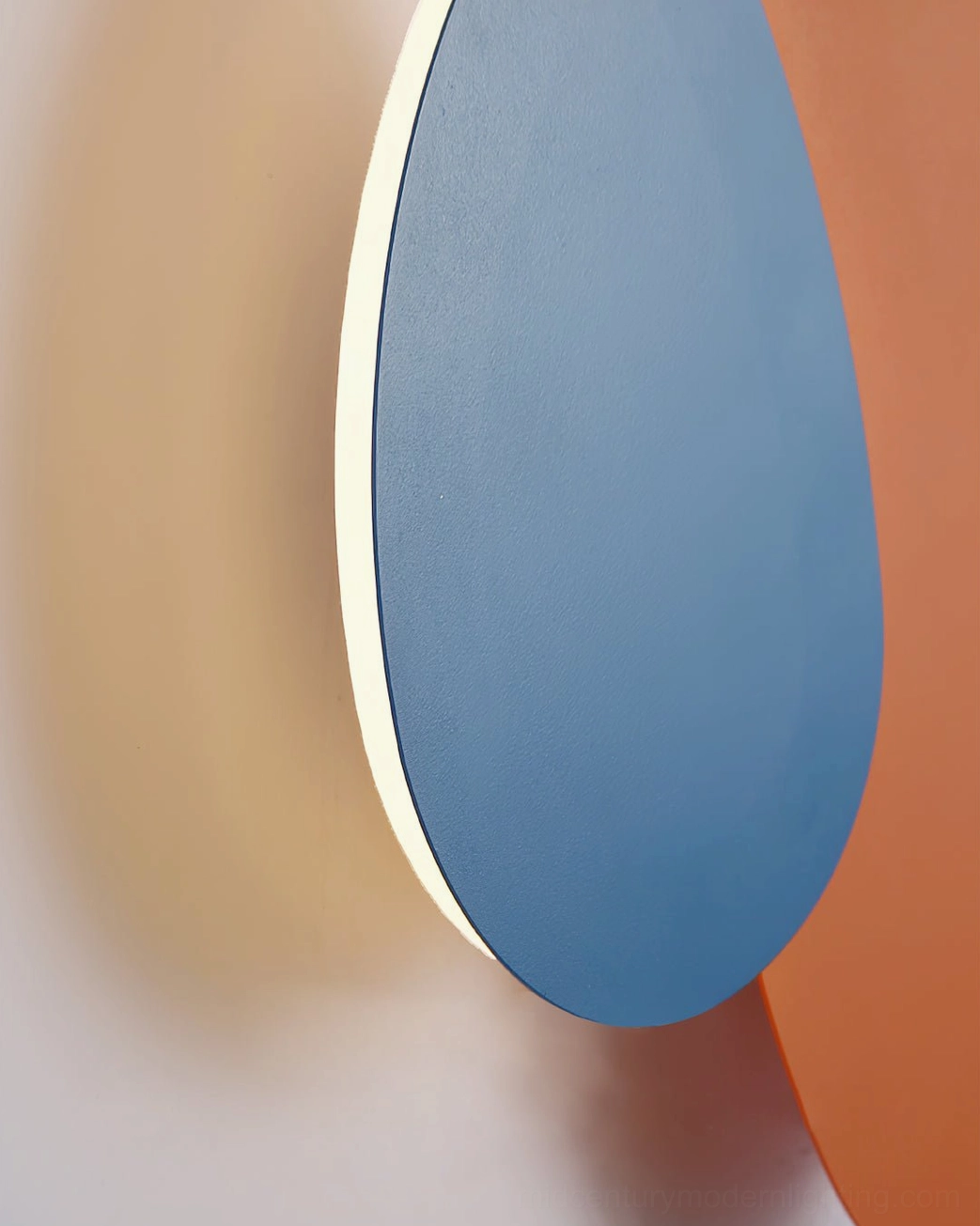 Tria modular wall lamp close-up frontal view showing matte finish and organic pebble form with soft glow