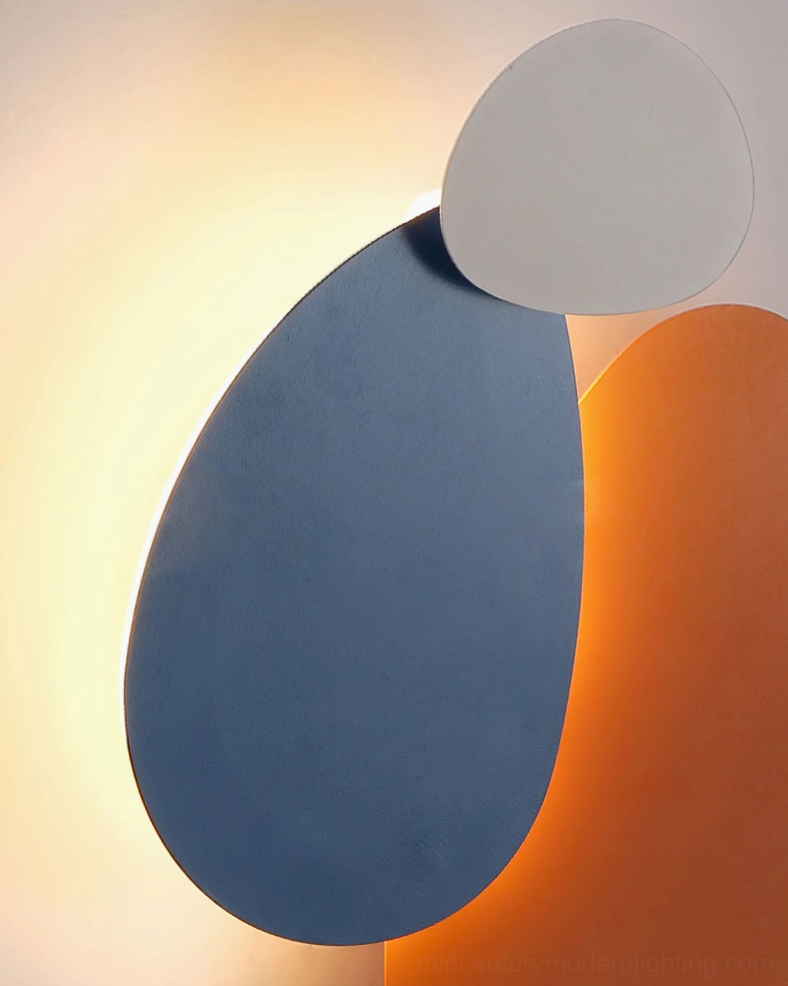 Close-up detail of Tria wall lamp showing smooth rounded pebble-shaped edges and warm backlit surface