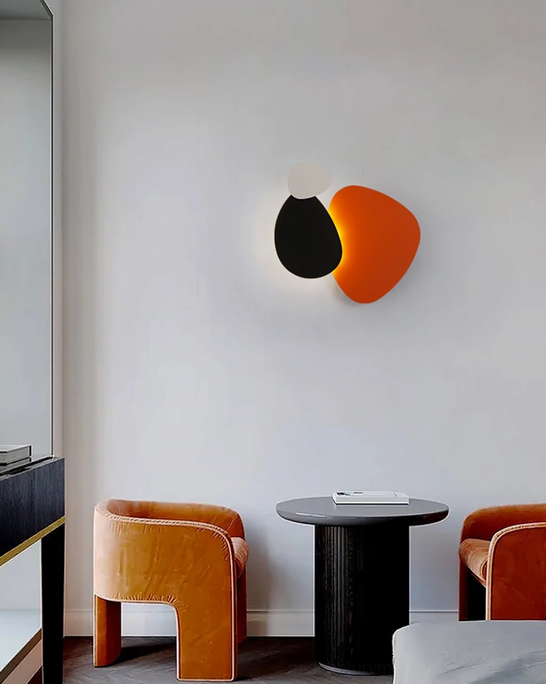 Tria black grey and orange LED wall lamp in contemporary living room with velvet seating and minimalist decor