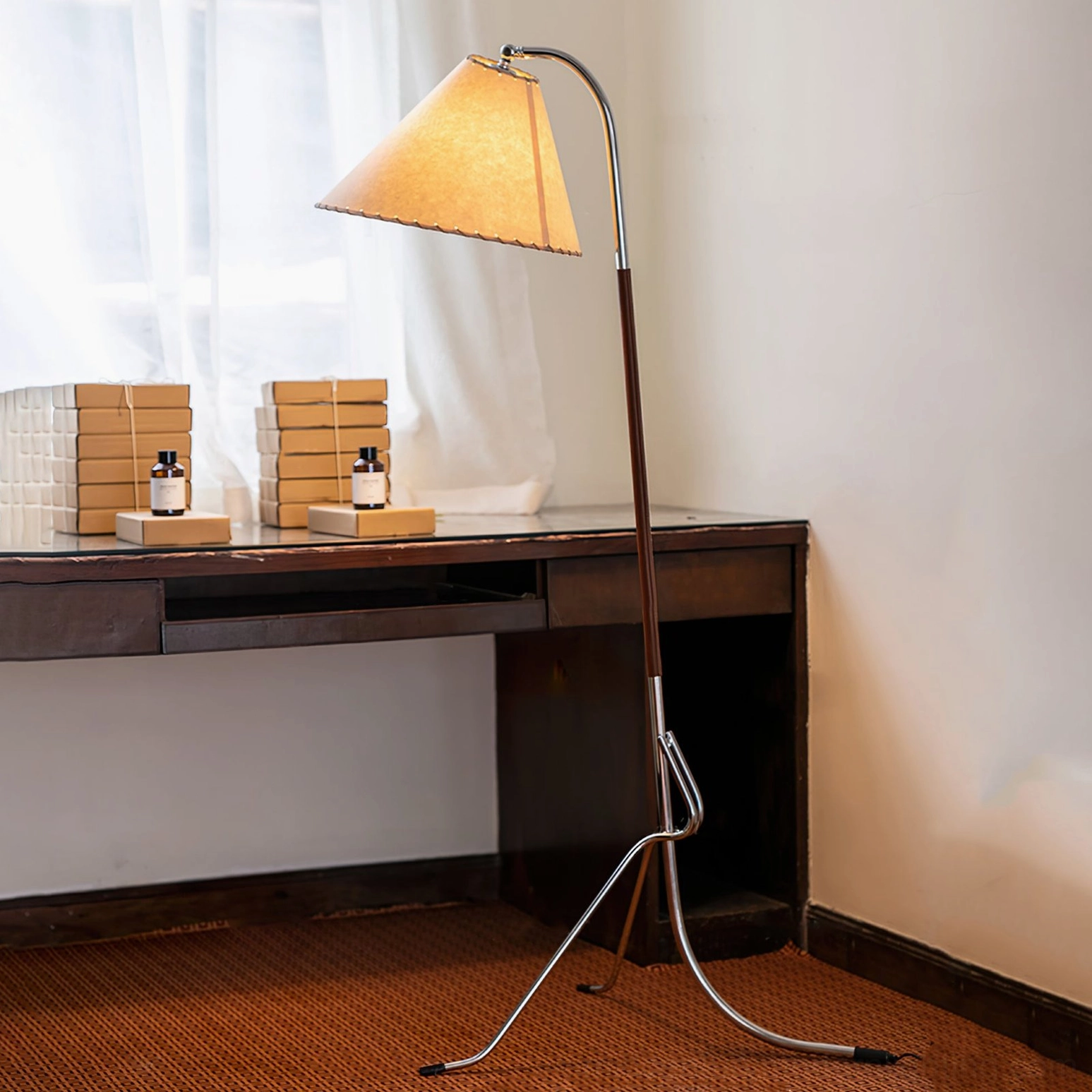 Tripod floor lamp in home study environment beside wooden desk, demonstrating warm ambient lighting in mid-century interior setting