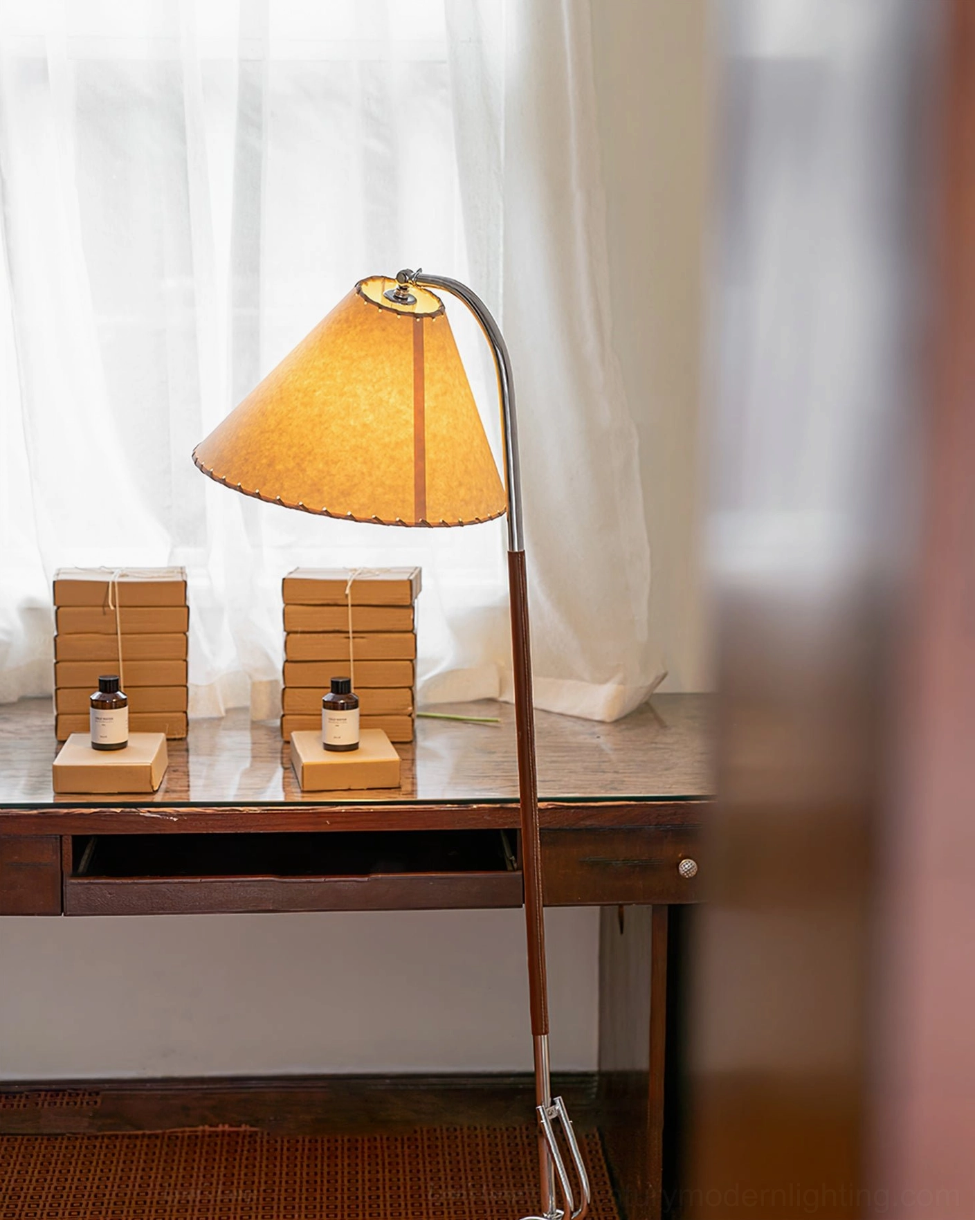 Low-angle detail view of tripod floor lamp showing silver metal tripod base and brown wooden pole with fabric shade construction