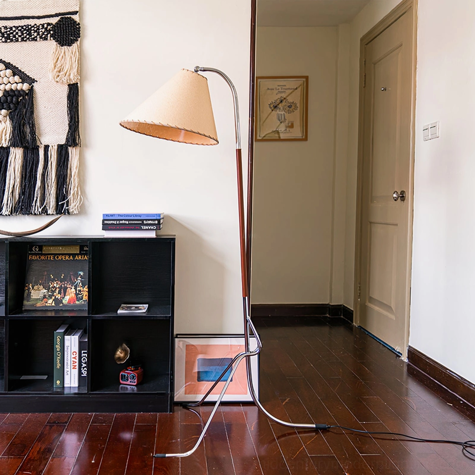 Tripod floor lamp beside black bookshelf in cozy living space with home decor accessories, demonstrating interior styling application