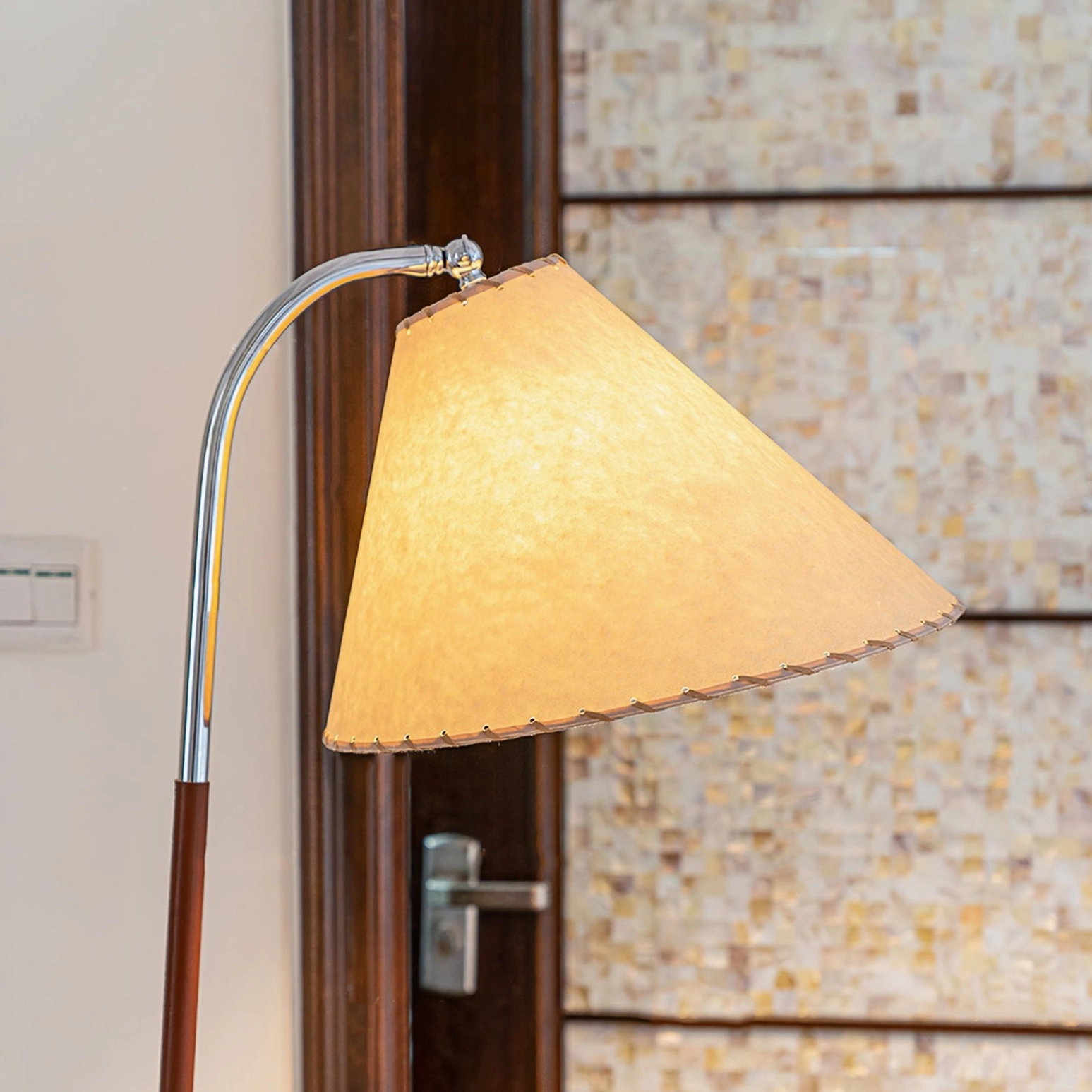 Side close-up of lamp pole and shade edge showing curved metal arm and scalloped fabric shade detail against tiled wall