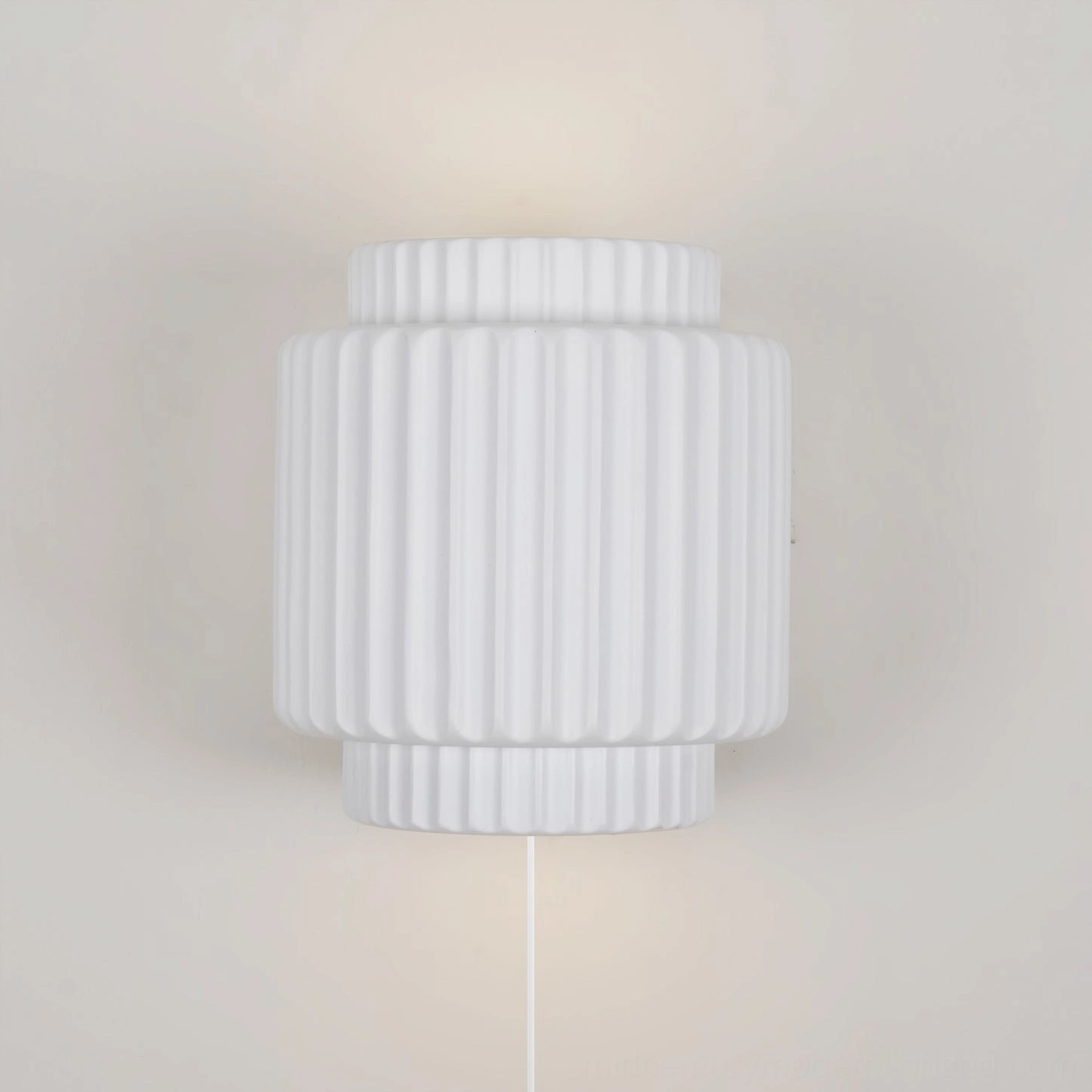 Tristan plug-in wall lamp mounted on plain indoor wall showing power cord and vertical fluted texture detail