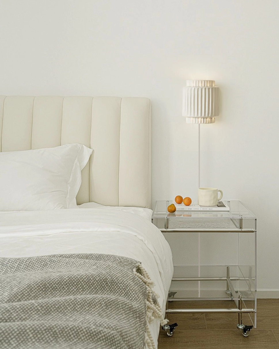 Tristan ribbed wall sconce mounted next to tufted headboard in minimalist bedroom with modern aesthetic