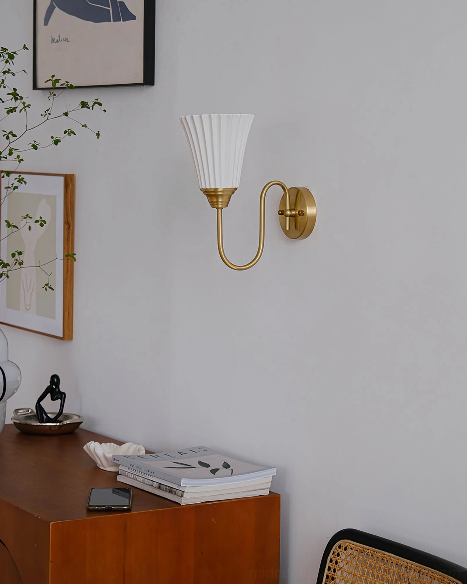 Mid-century modern wall sconce with brass arm installed above console in decorated home nook