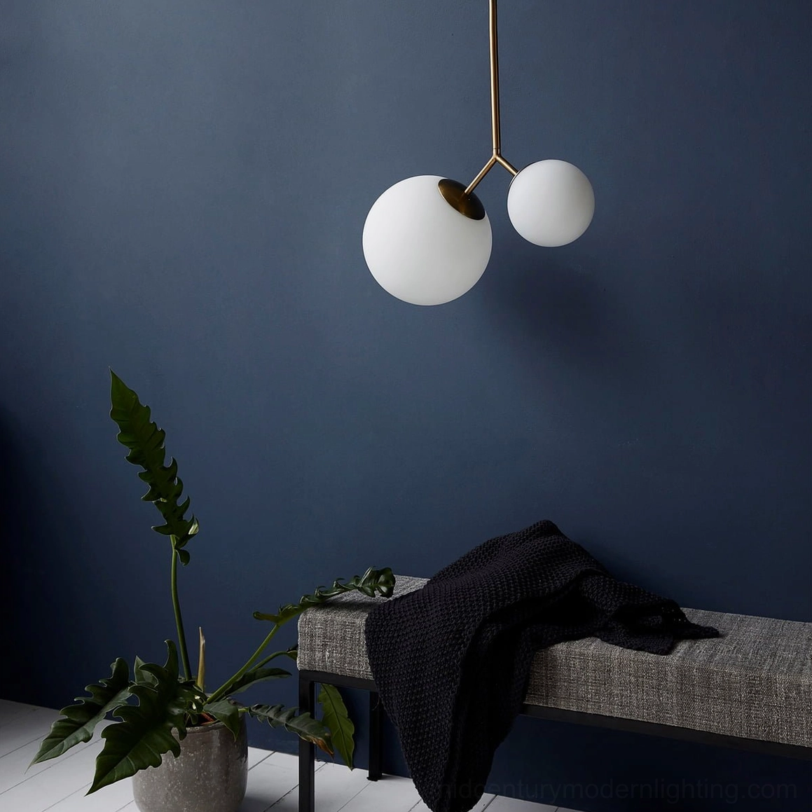 Twis frosted globe pendant lamp with gold metal frame and navy accent wall in contemporary entry bench nook
