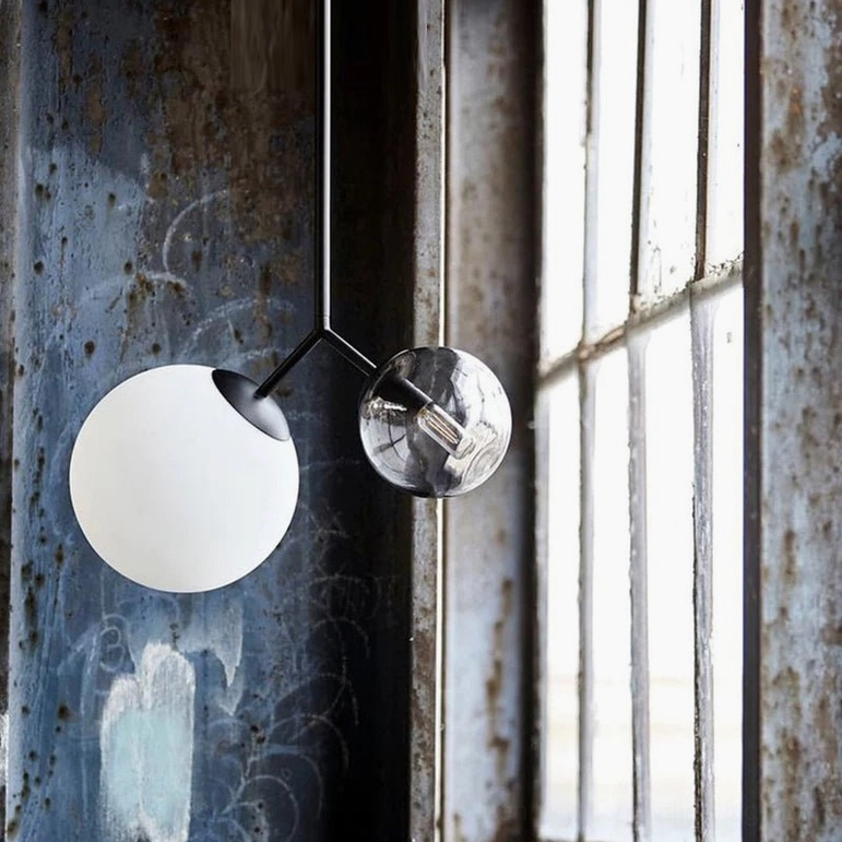 Twis asymmetric pendant lamp with black metal rod and mixed glass shades in industrial style window area