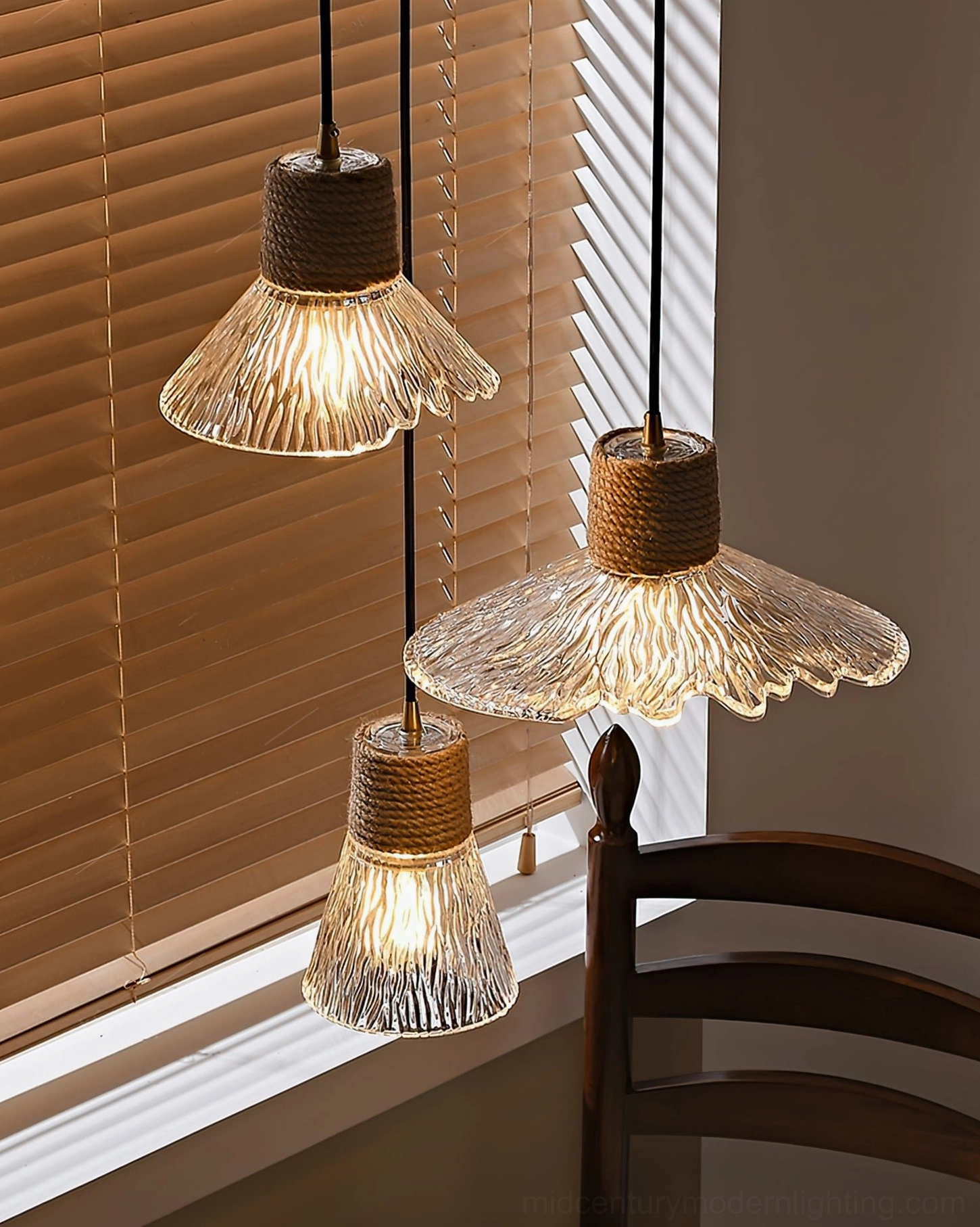 Two hemp rope glass pendant lights with varying opaque glass shades in dining space, warm mixed interior styling