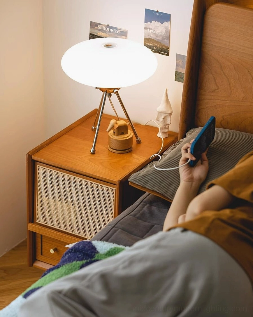 UFO table lamp on retro wooden nightstand, bedroom ambiance with person relaxing in background
