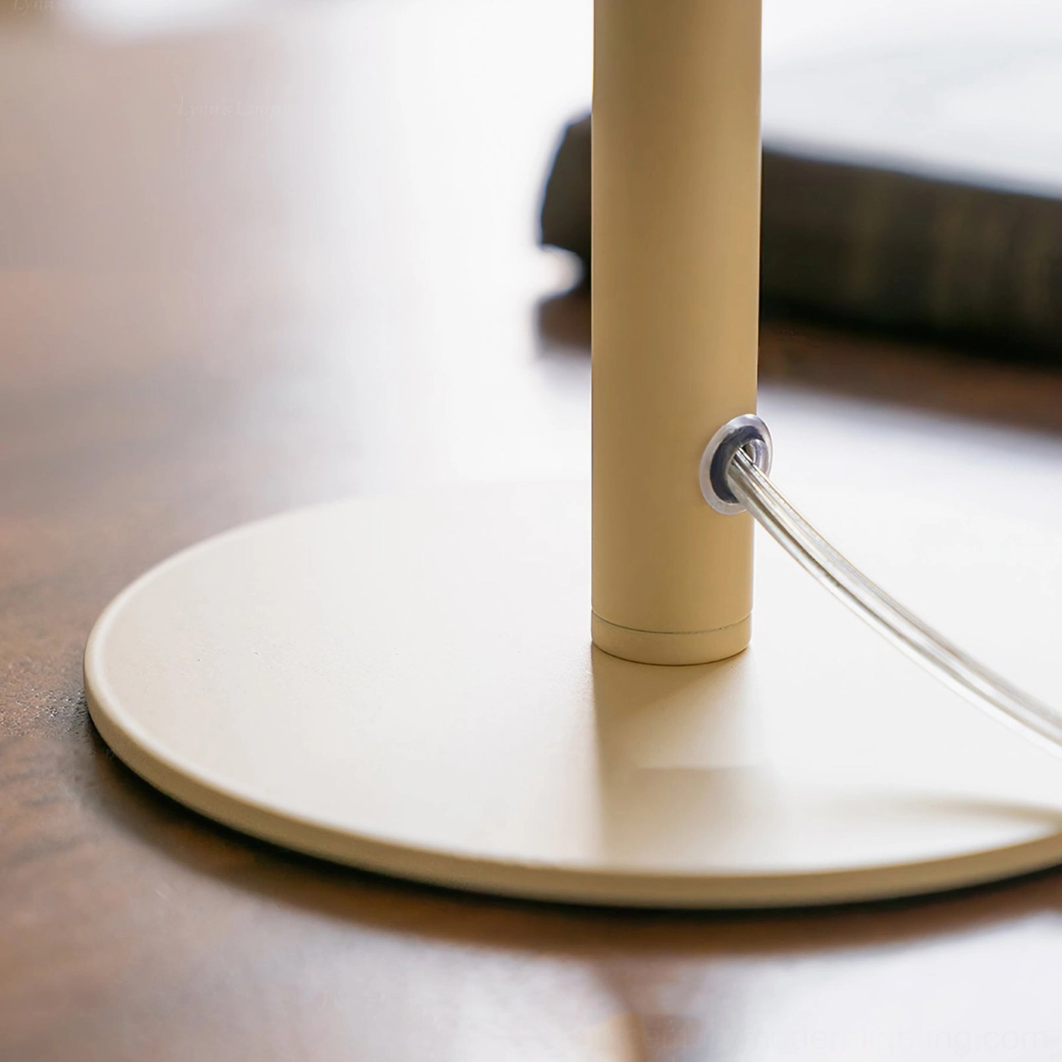 Valencia table lamp base and power cord assembly detail on polished wooden tabletop, matte cream metal