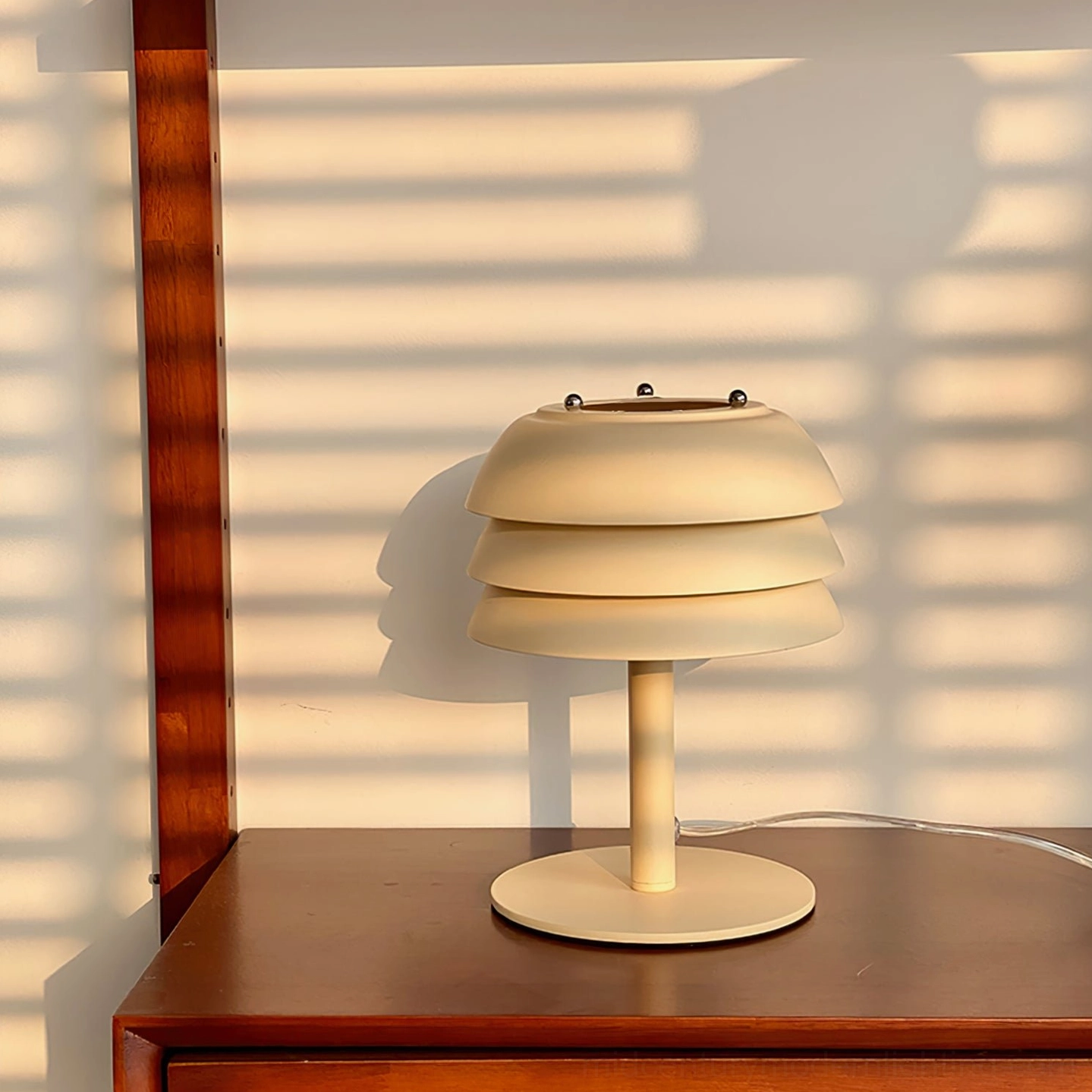 Valencia cream table lamp on wooden desk with mid-century decor, warm soft lighting from tiered design
