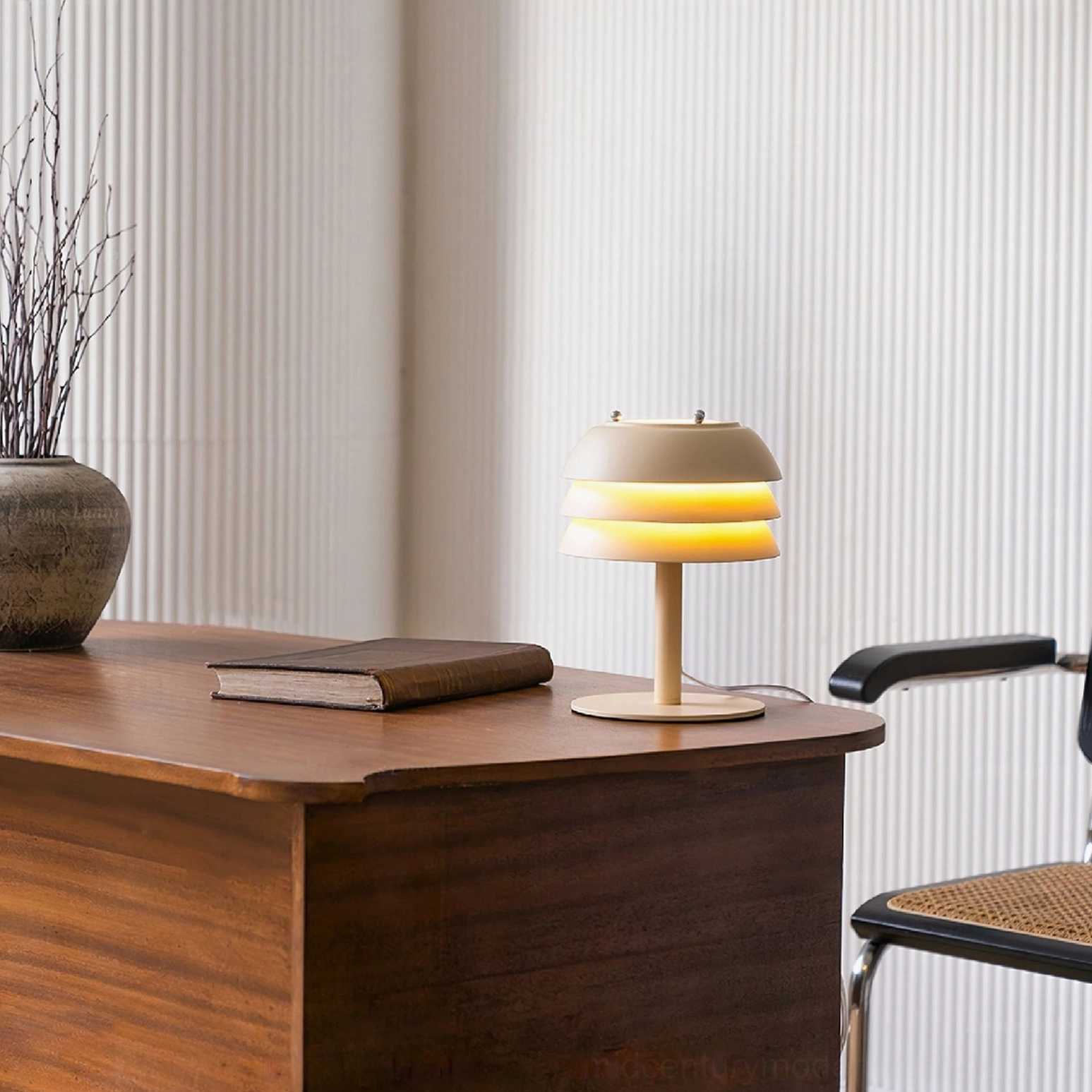 Valencia illuminated table lamp casting warm ambient light from tiered design on desk with rattan chair