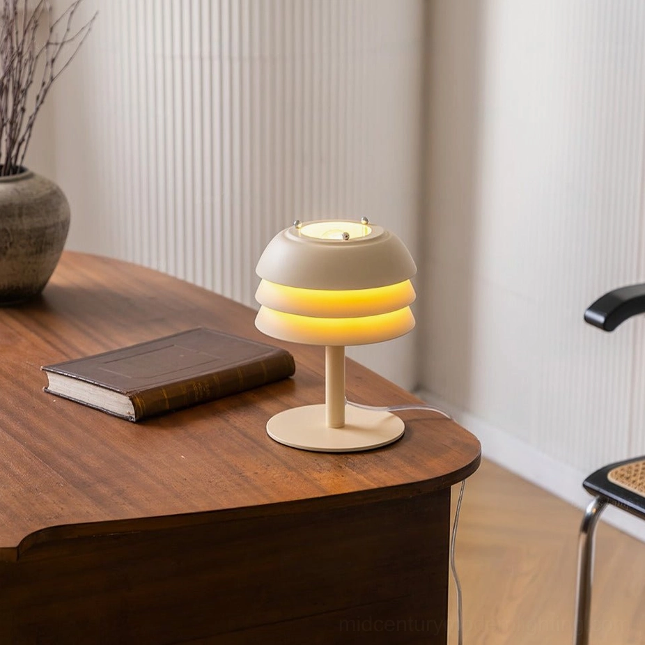 Valencia tiered lamp illuminated, warm yellow glow on wooden desk with ribbed wall backdrop, ambient lighting