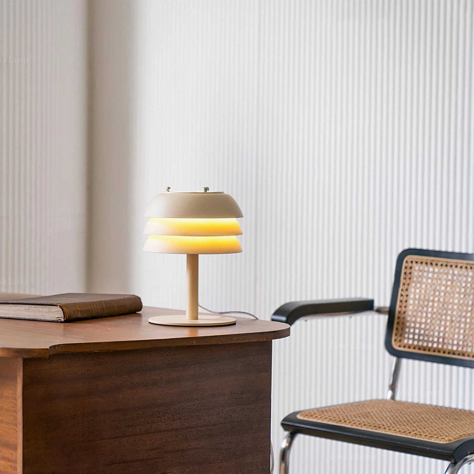 Valencia tiered lamp glowing with warm interior light on wooden desk, rattan chair and vintage book styling