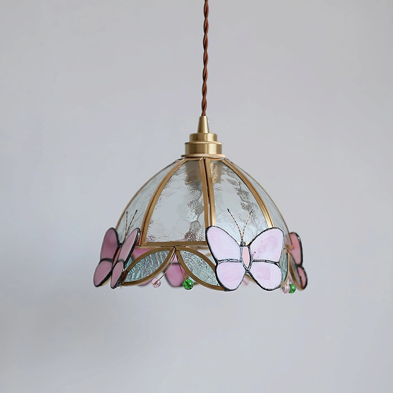 Low-angle front view of Valinte pendant with lavender-toned butterfly stained glass and water-textured glass shade creating light diffusion