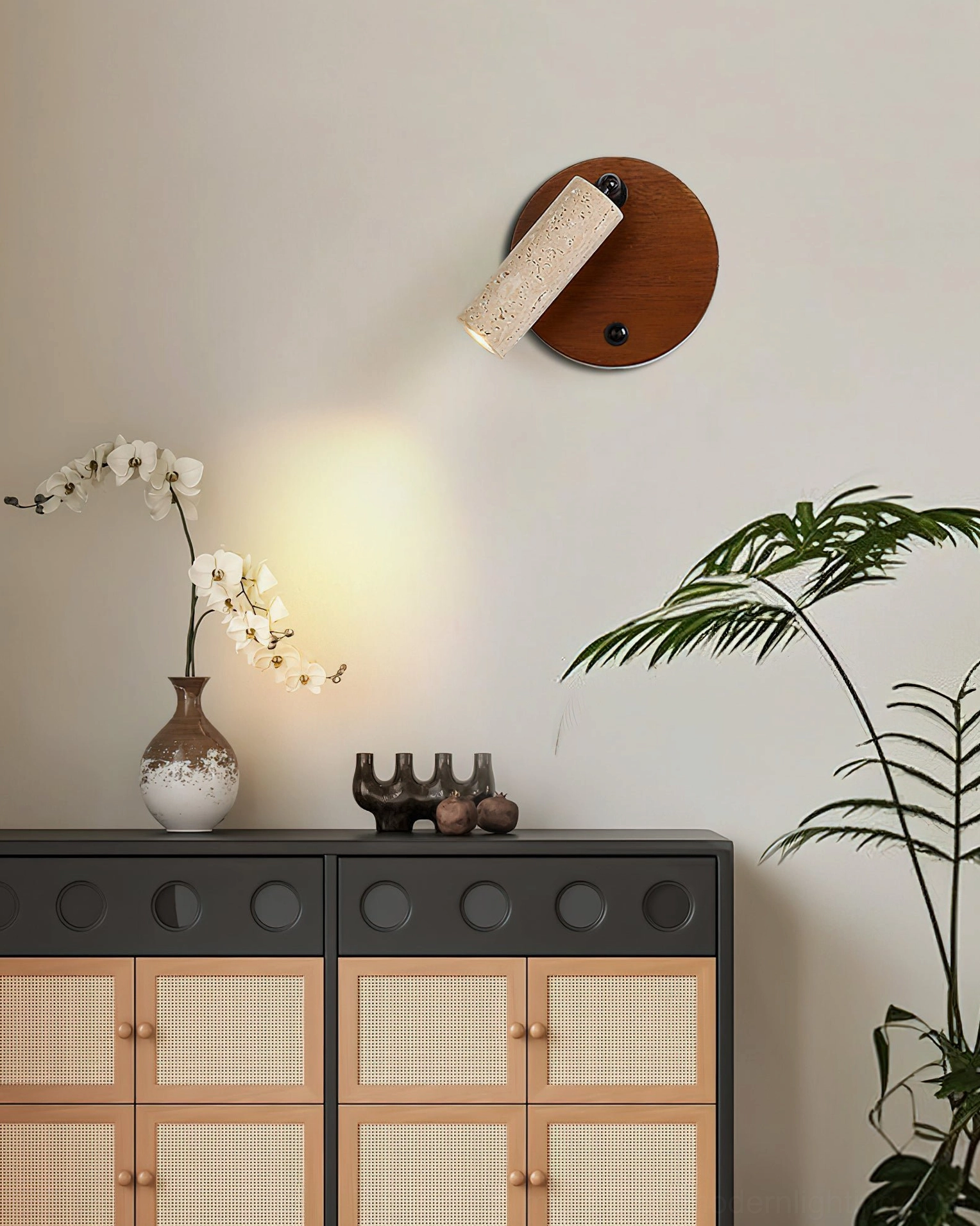 Veda travertine wall sconce styled in living room with rattan storage cabinet and floral accents