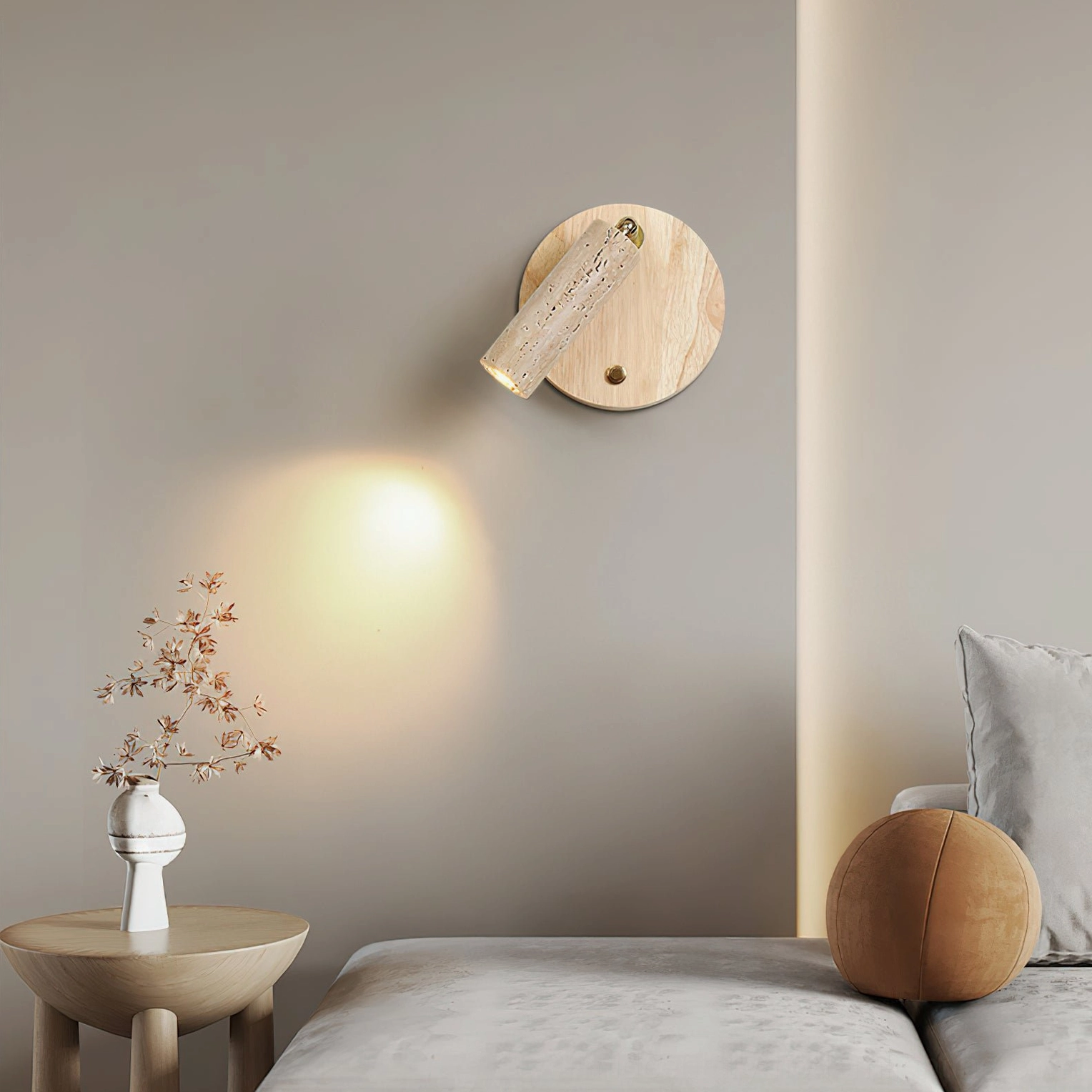 Veda travertine wall lamp creating warm wash lighting effect in minimalist bedroom space