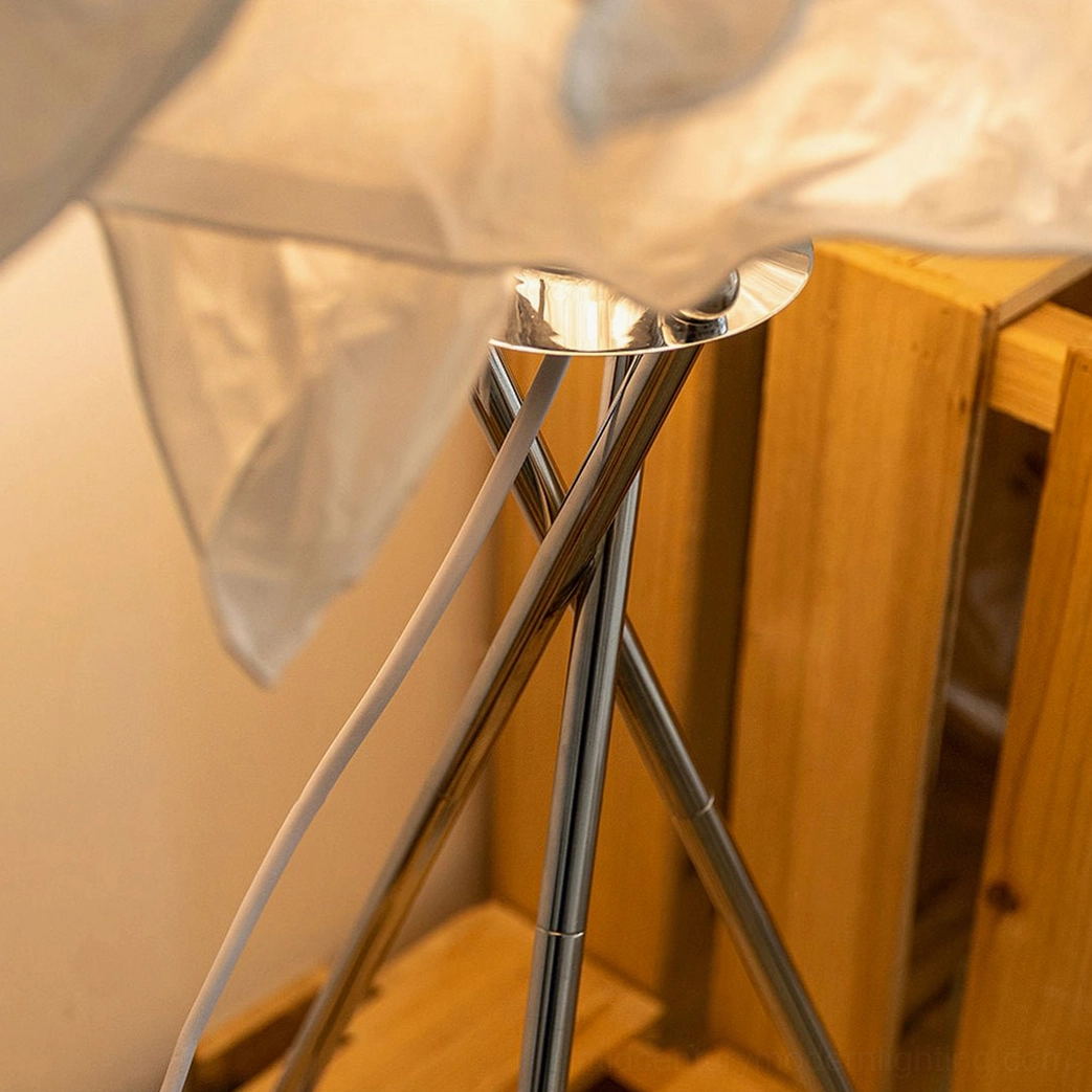 Close-up of Veli lamp hardware showing chrome metal tripod base, white mulberry paper shade, and power cord connections