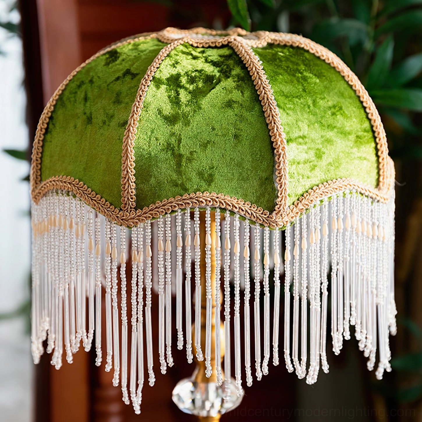 Close-up detail of green velvet lampshade with gold braided trim and beaded tassel fringe