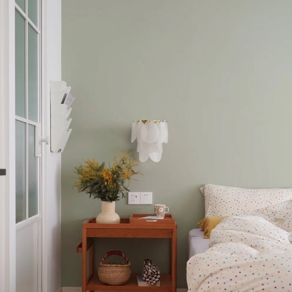Lit Verbier wall sconce glowing warm amber light through frosted glass leaf layers on muted green wall