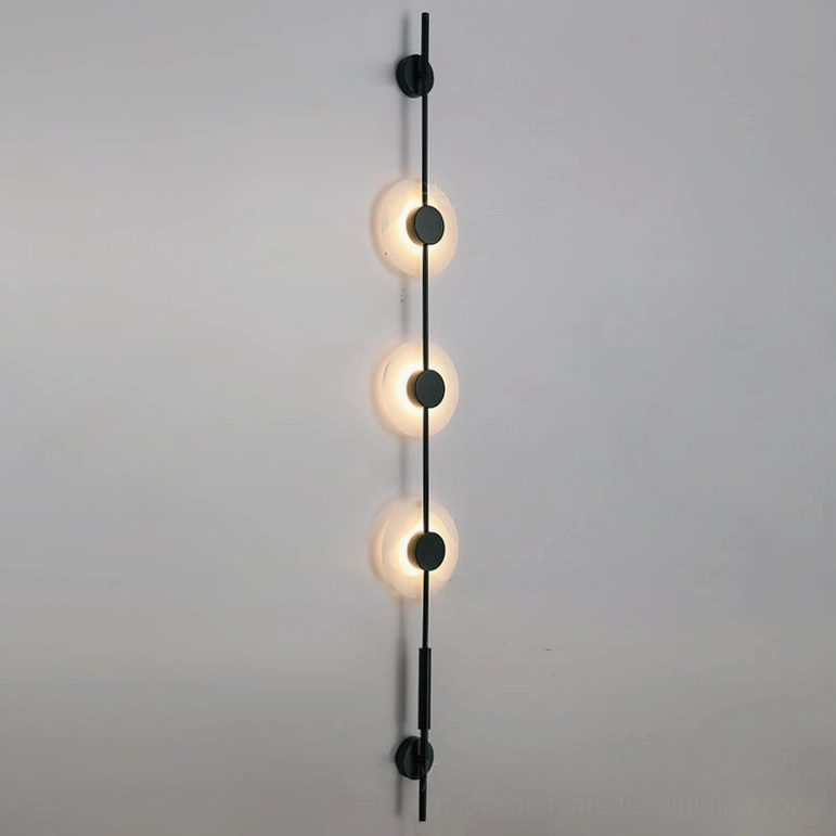 Three-light vertical alabaster wall lamp in matte black finish displayed on neutral gray studio background showing complete proportions