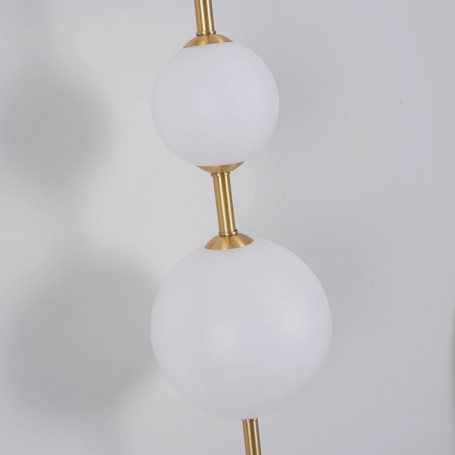 Vertical globe wall lamp detail shot showing brass frame and frosted sphere assembly with mounting bracket