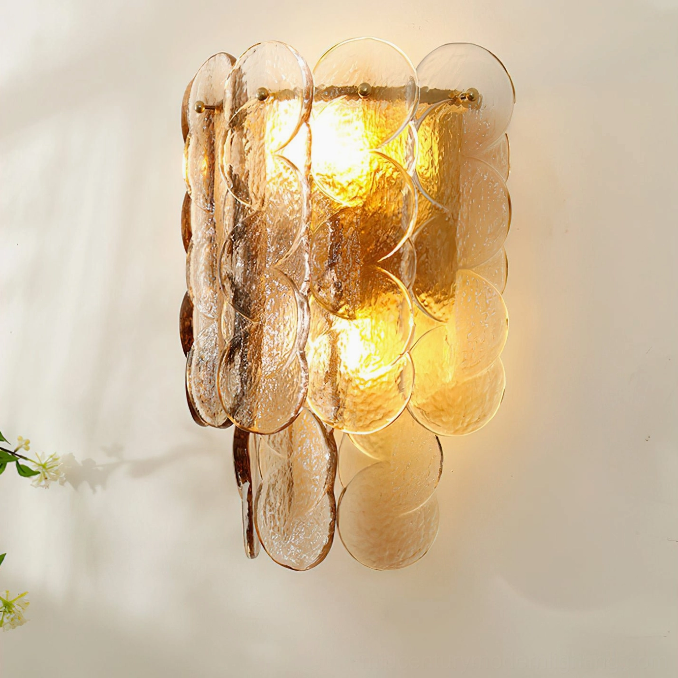 Vertical tiered glass wall sconce with slim silhouette casting bright warm glow
