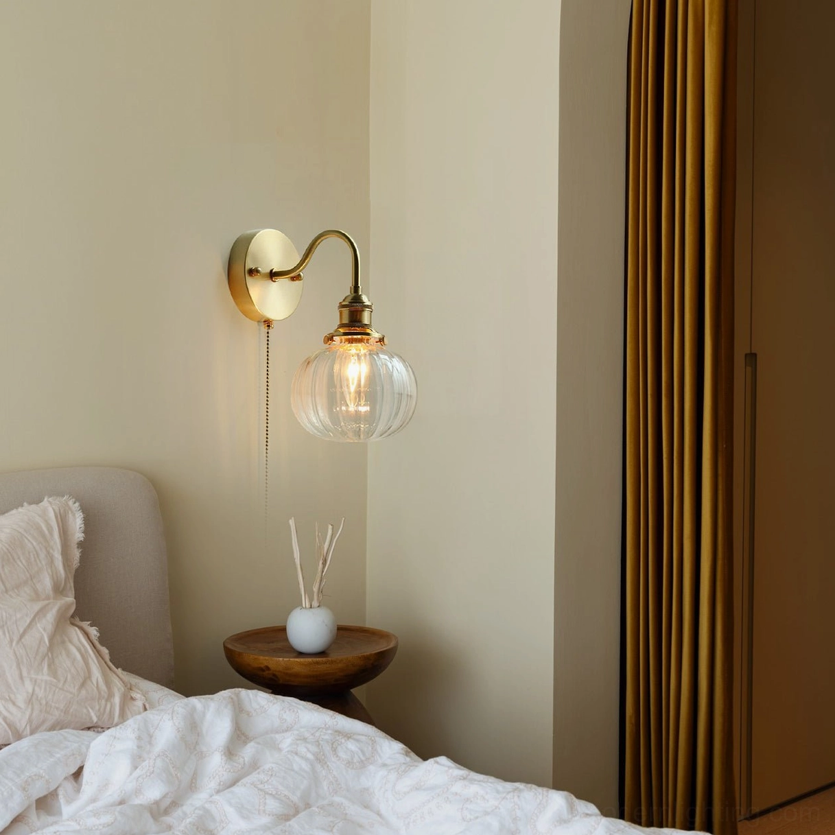 Brass wall lamp mounted bedside with warm Edison bulb glow - cozy bedroom mid-century lighting setup