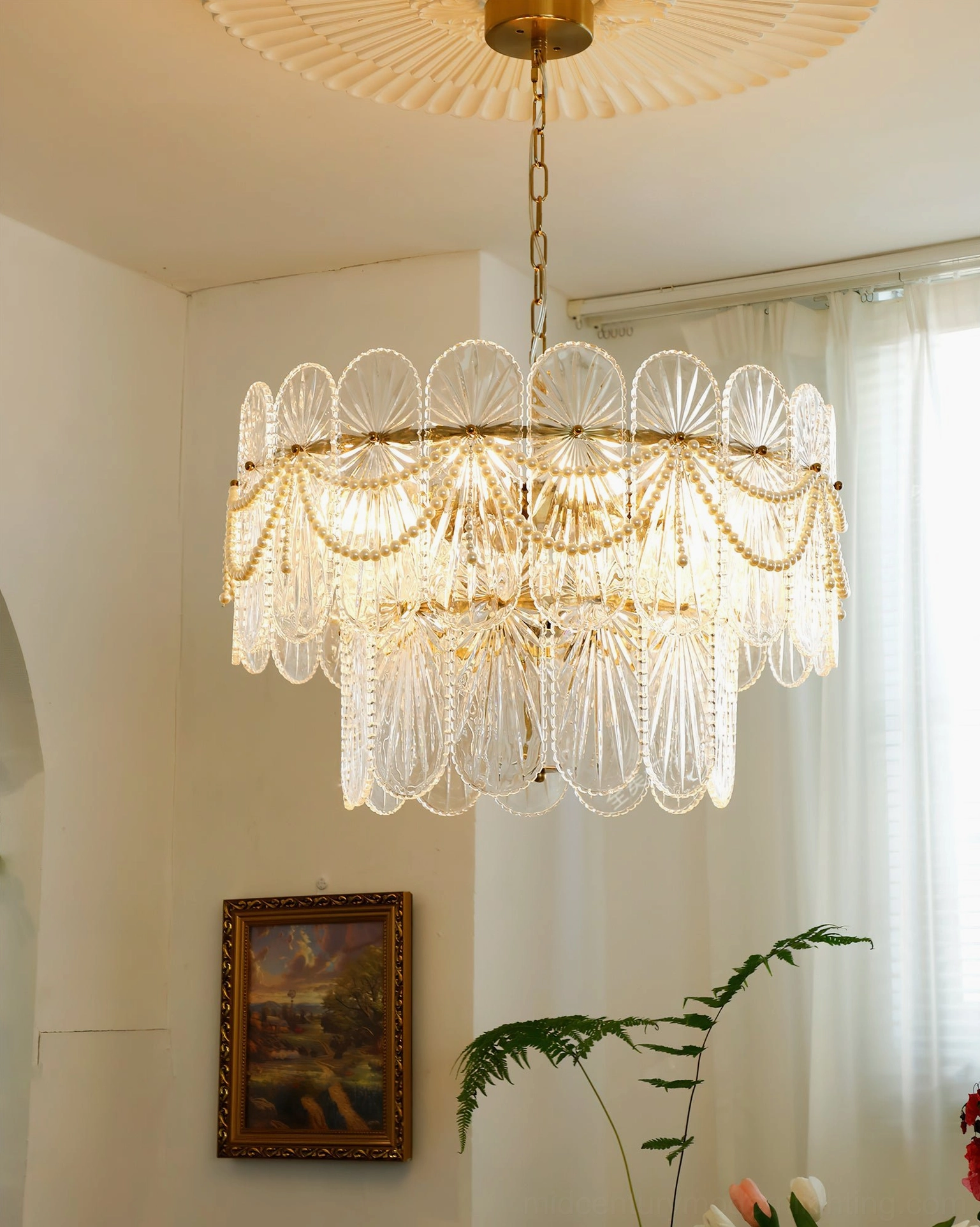 Two-tiered vintage glass chandelier with gold frame and matching ceiling rose in residential space with artwork