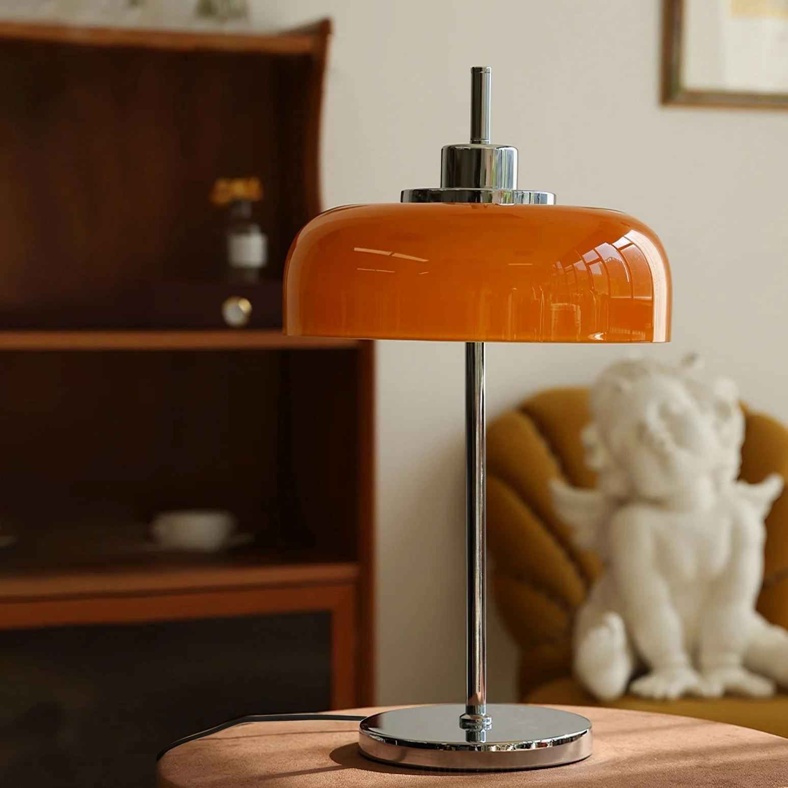 Vintage-inspired orange table lamp displayed in living room with wooden cabinet and decorative angel statue