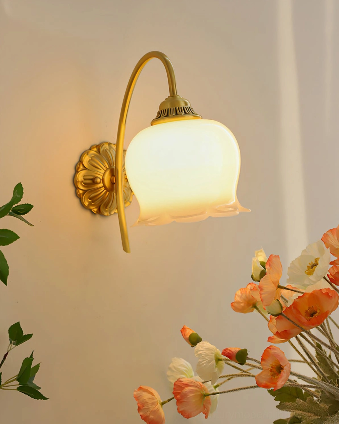 Illuminated lily of the valley wall lamp with warm light glowing through frosted glass shade beside flowers