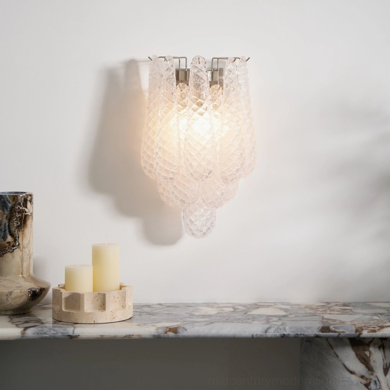 Clear glass Viola Drop wall sconce mounted above marble console table