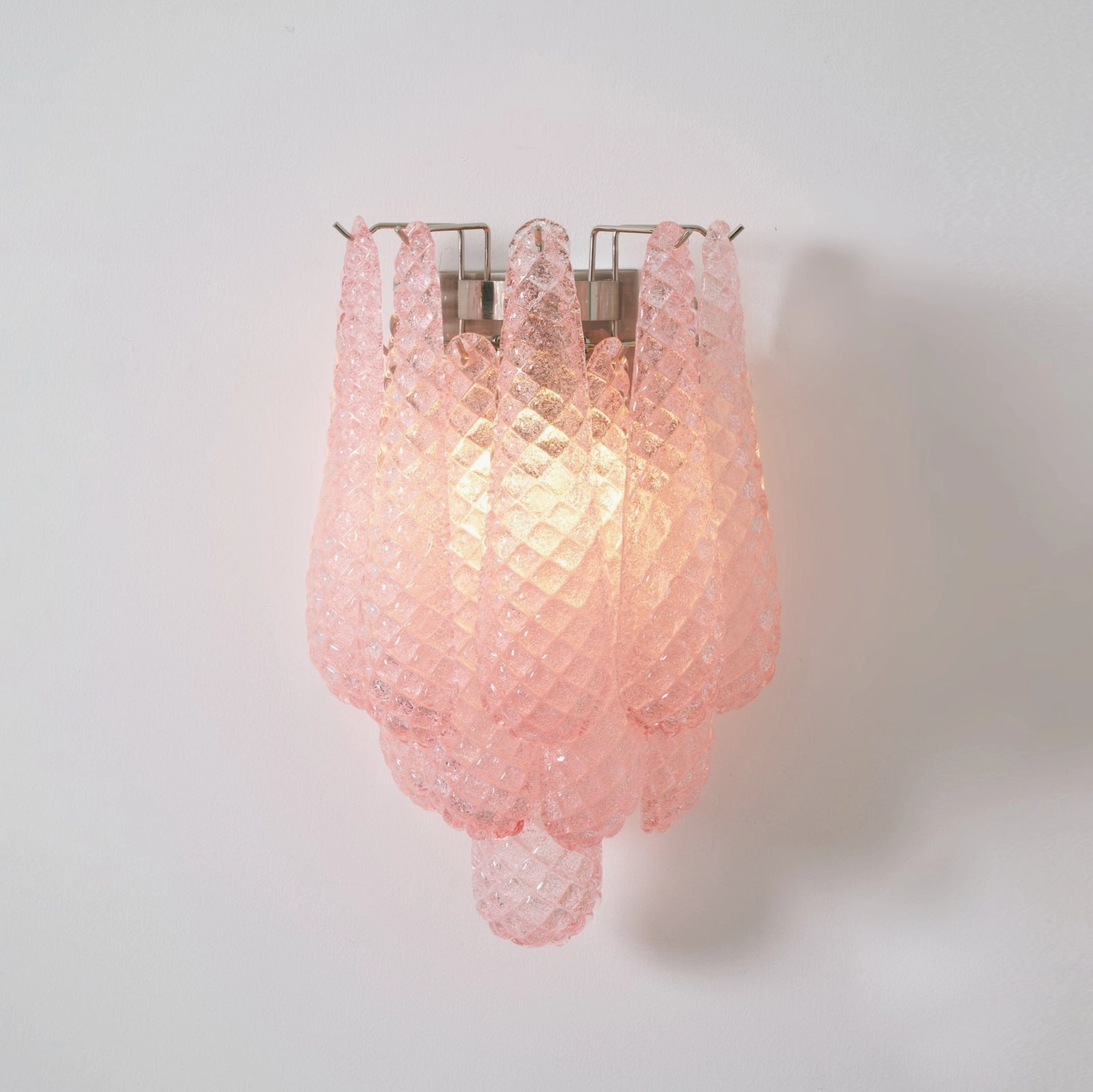 Illuminated pink Viola Drop Murano glass wall sconce emitting warm ambient light