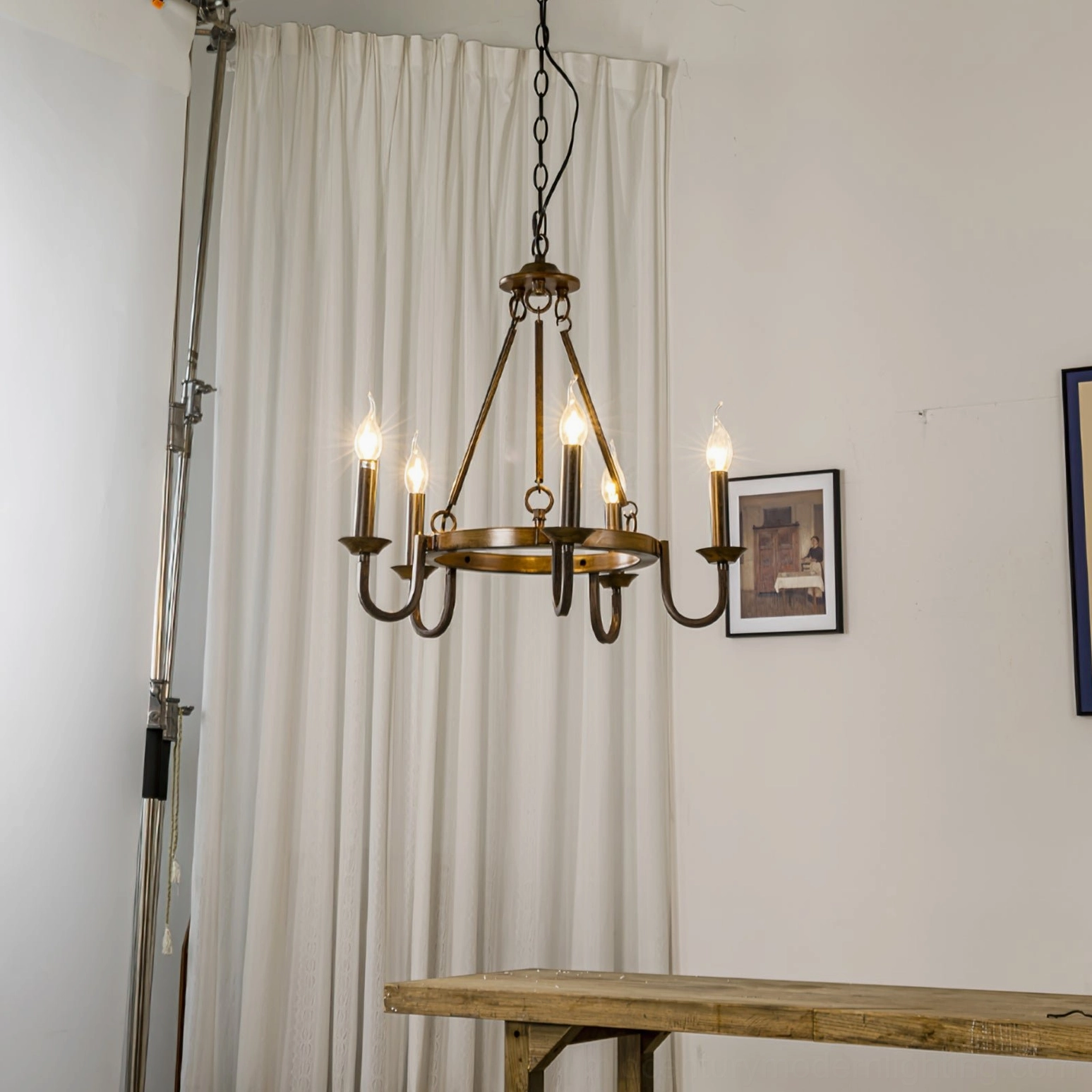Wagon wheel chandelier styled in farmhouse room with vintage wall art and wooden accents