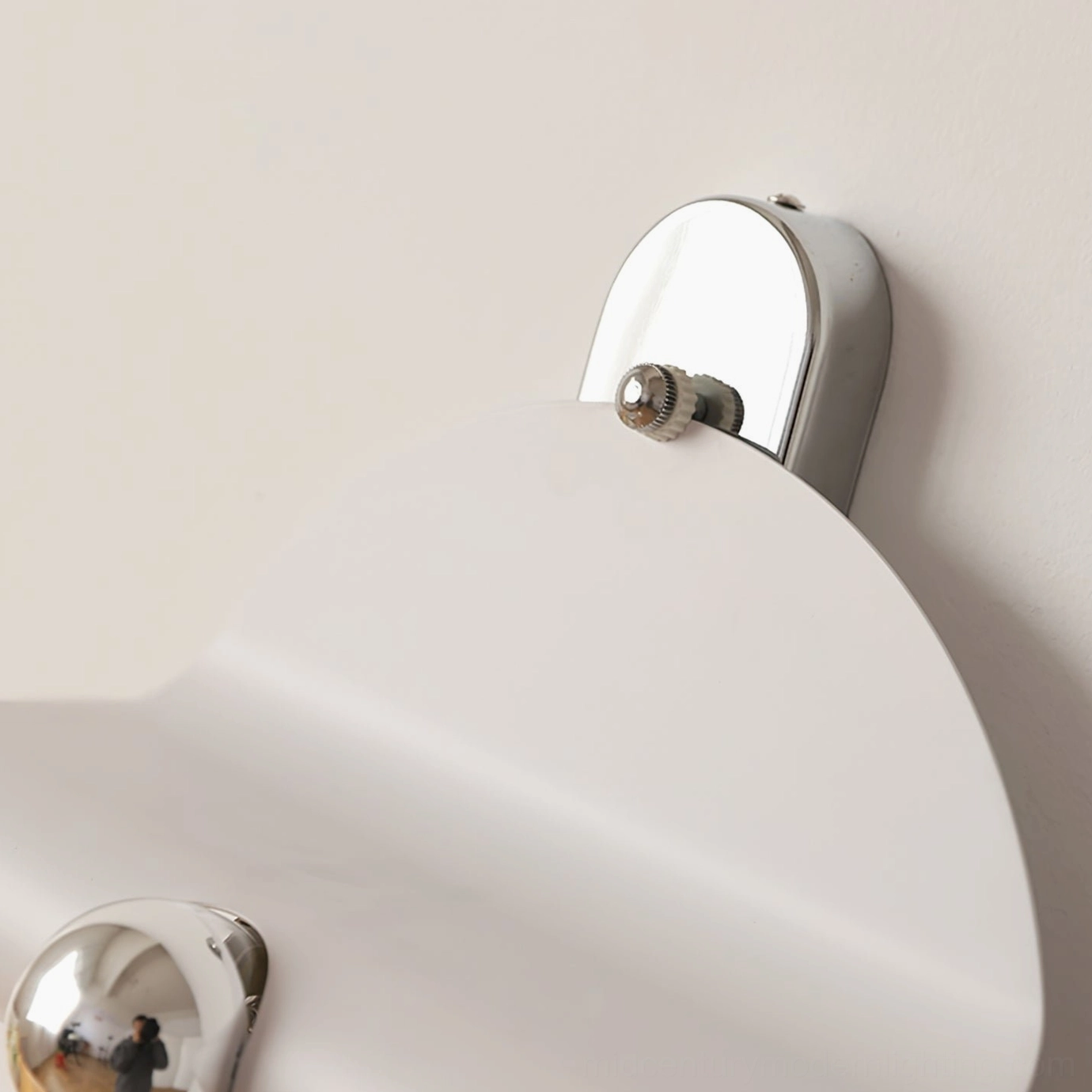 Close-up detail of chrome metal bracket and mounting hardware of minimalist wall sconce